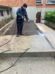 agent d'entretien nettoie une dalle avec un nettoyeur haute pression